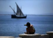 man-drinks-beer-at-the-cais-das-colunas-as-caravel-sails-by-on-targus-river-in-lisbon-portugal